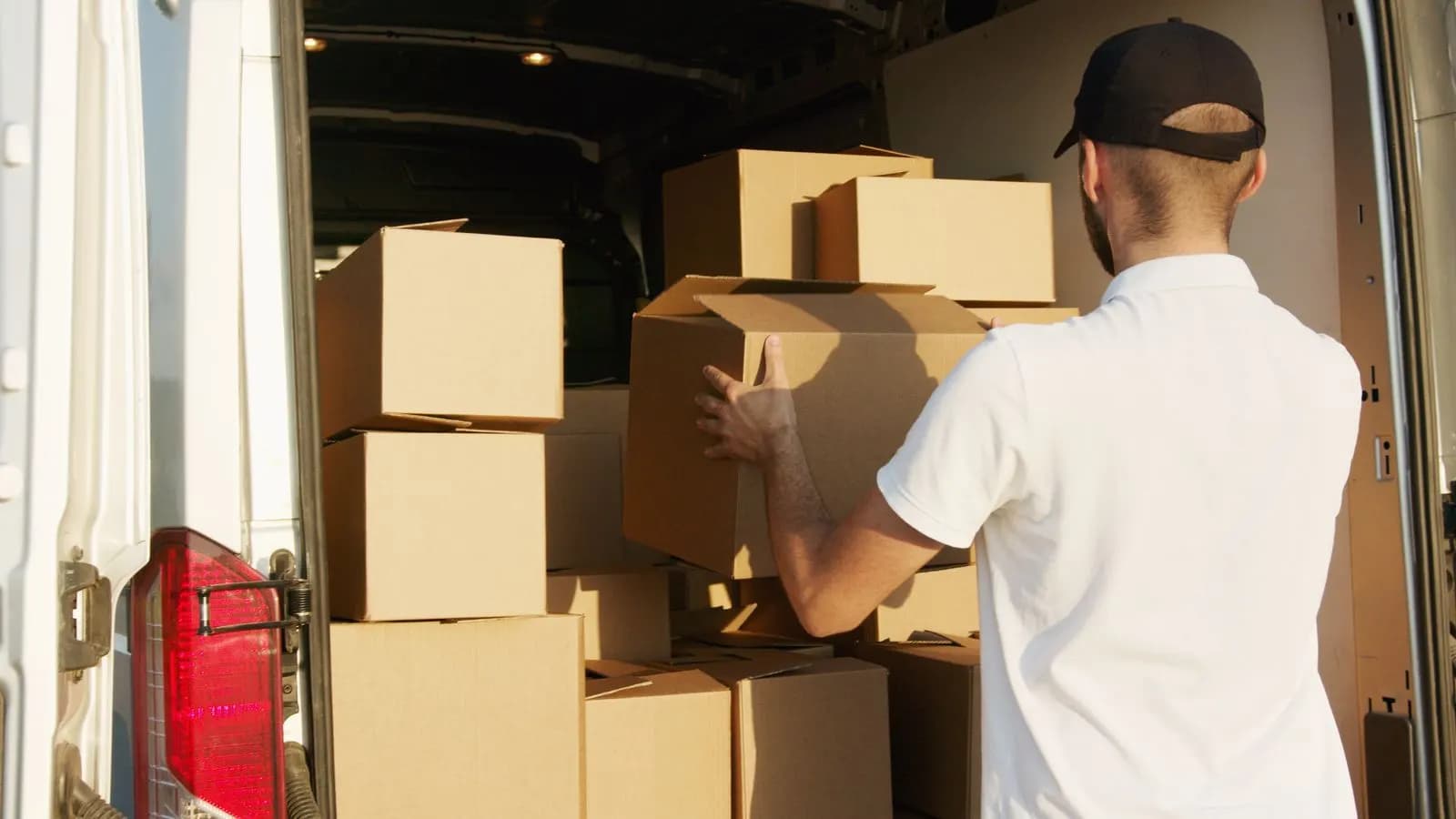 A courier loading boxes into a van